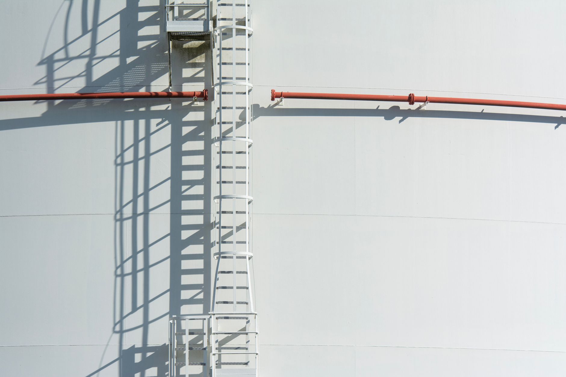 Worker climbing a fixed ladder in an industrial facility
