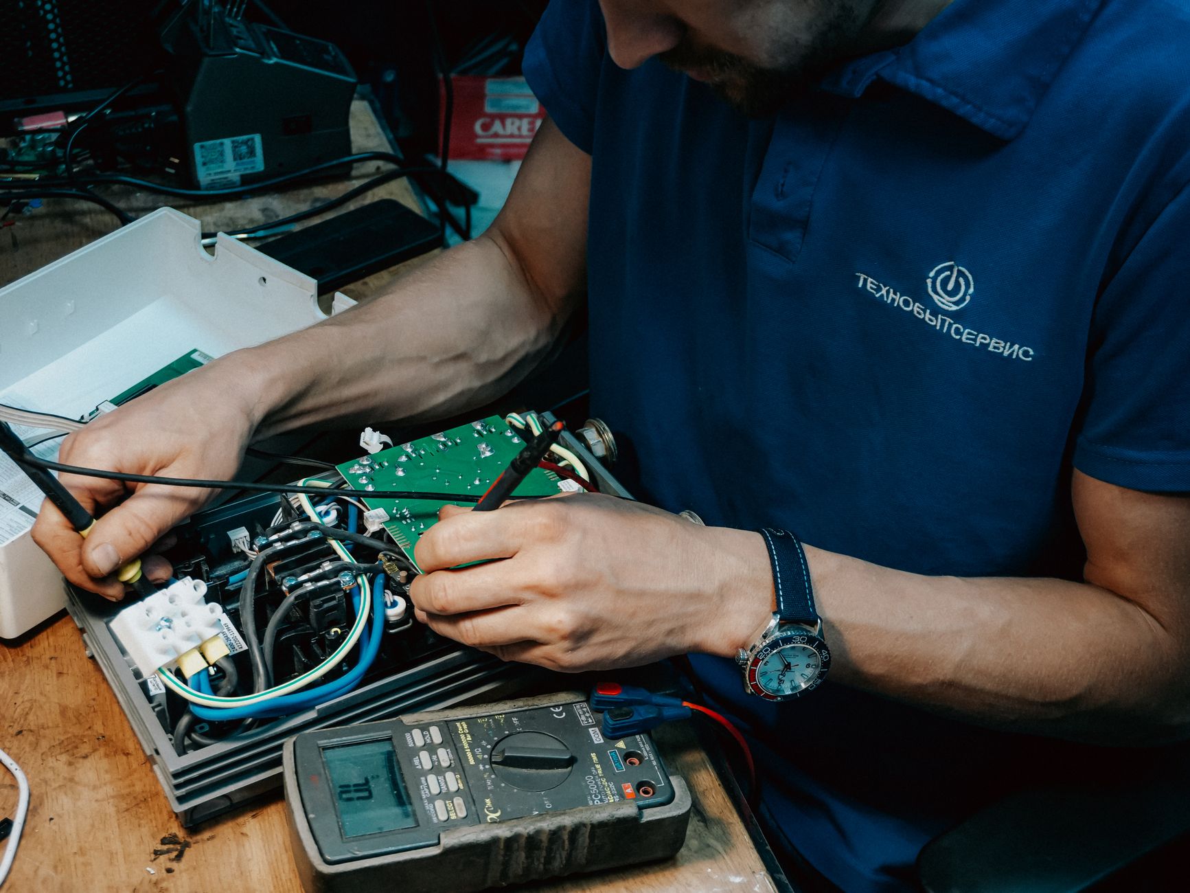 Technician testing voltage with a multimeter on a control panel