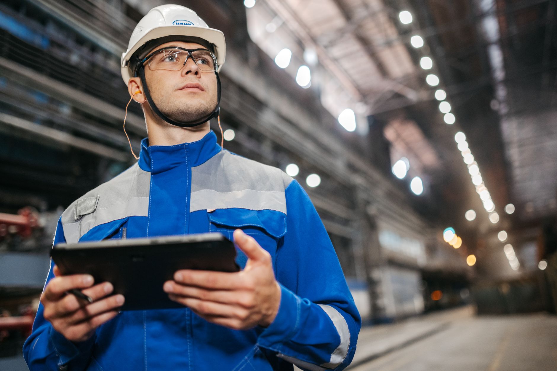 Plant worker reviewing equipment data on a tablet on the production floor