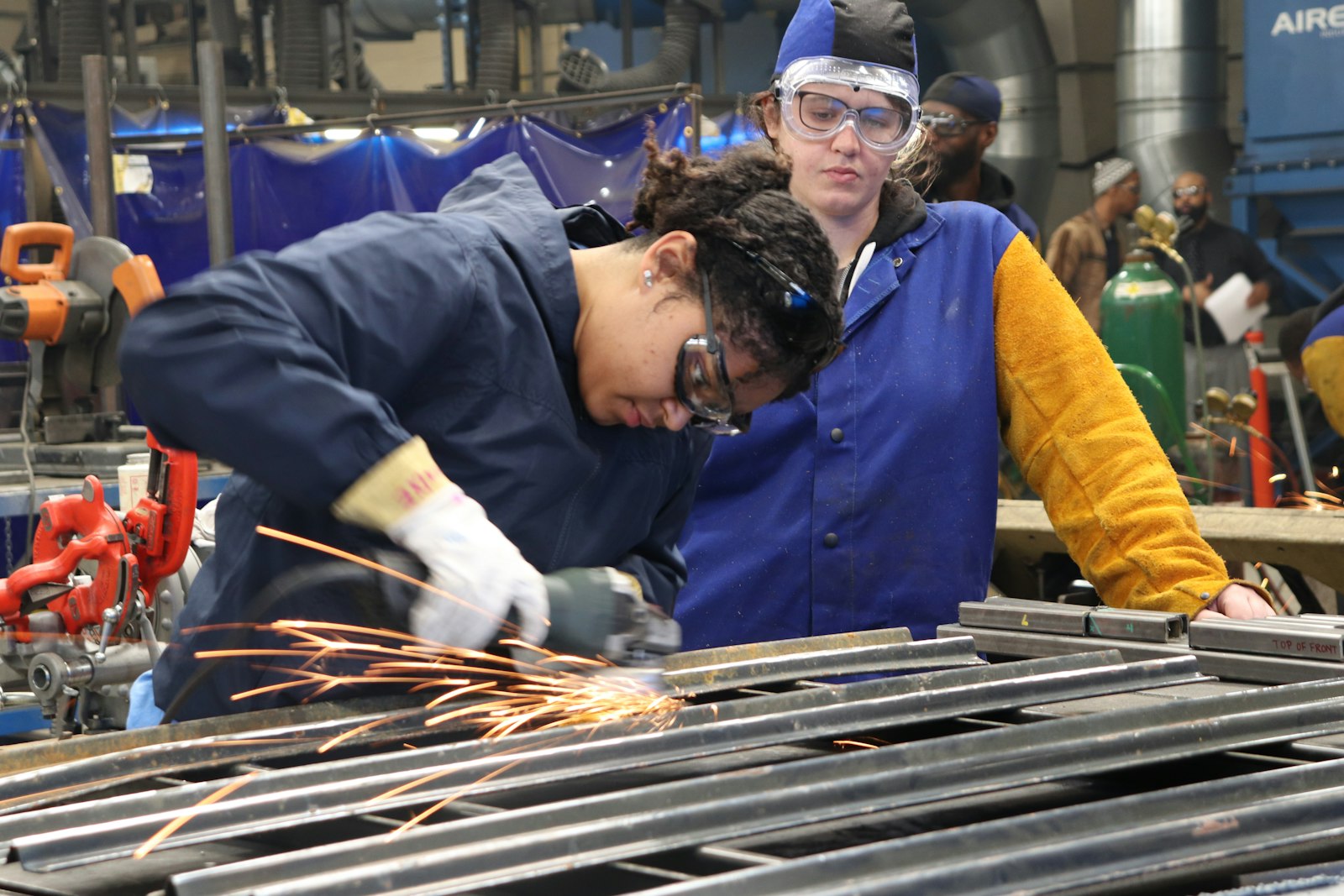 Trade school students in welding training with sparks flying