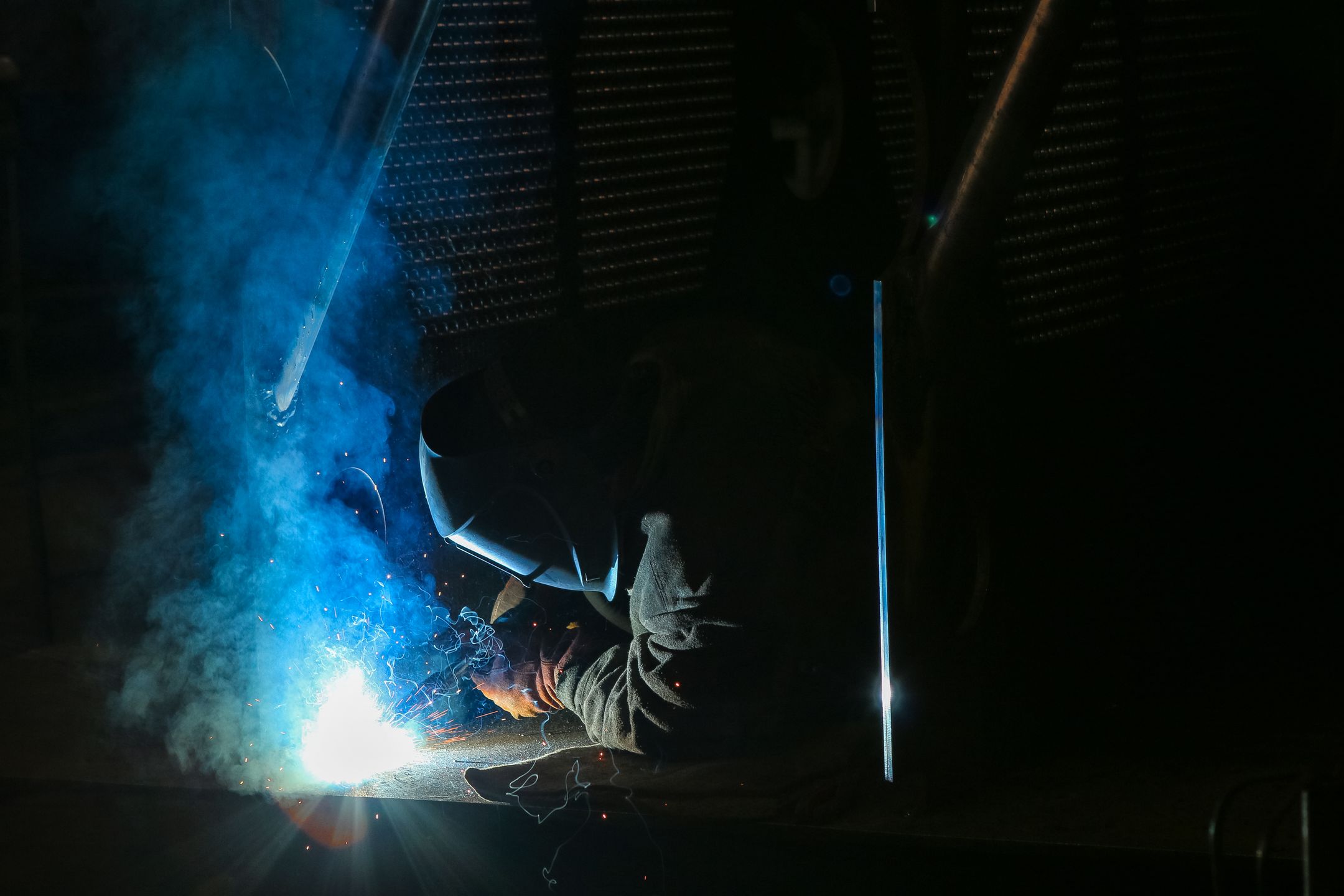 Welder wearing protective gear with sparks and smoke